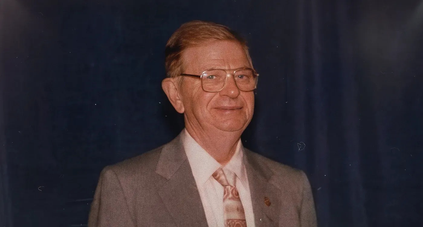 Archival portrait of Terry Hines wearing glasses, a suit, and a patterned tie