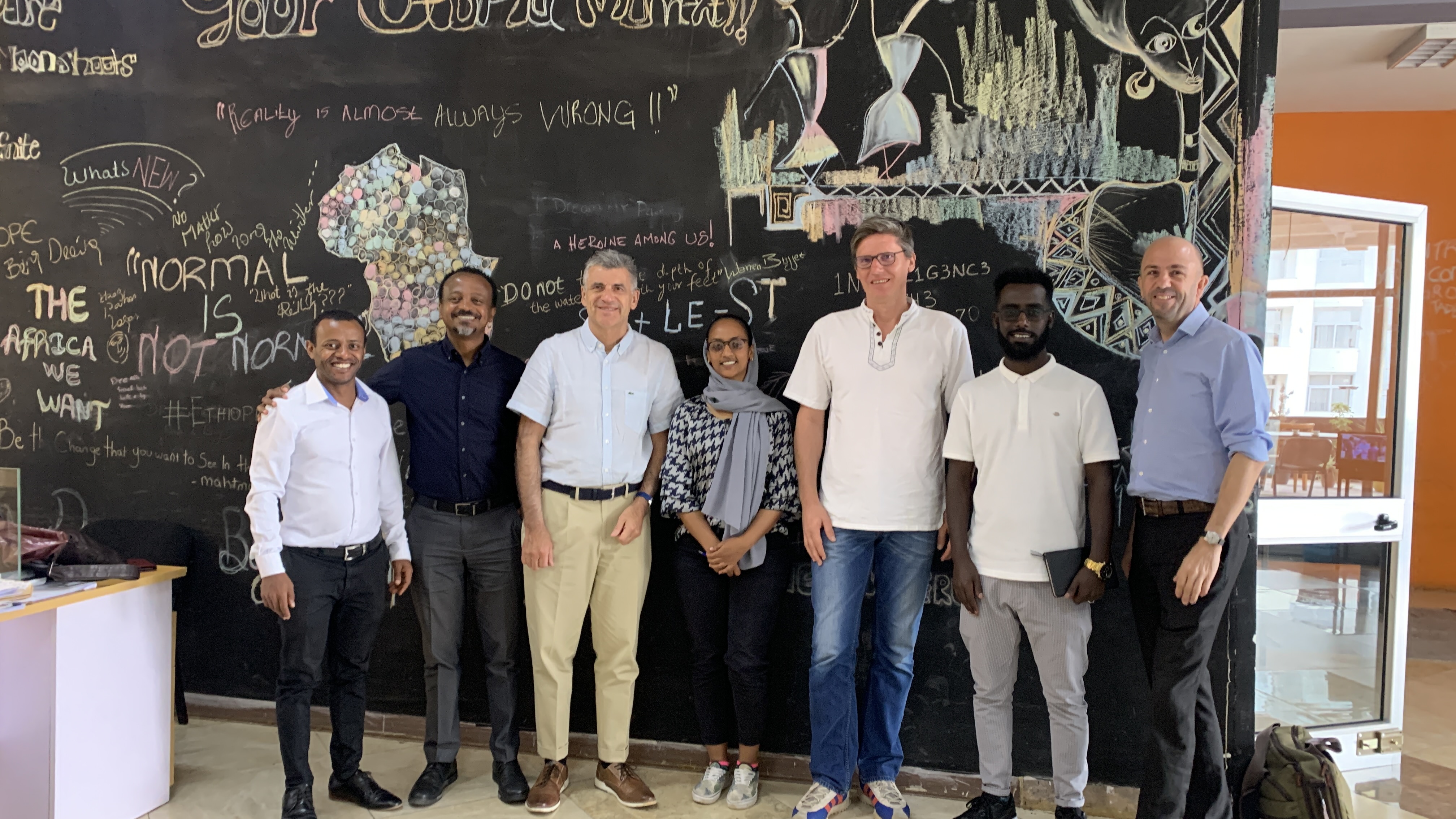 Seven xHub and partner representatives stand before a chalkboard; Tewodros Tadesse is second from left.
