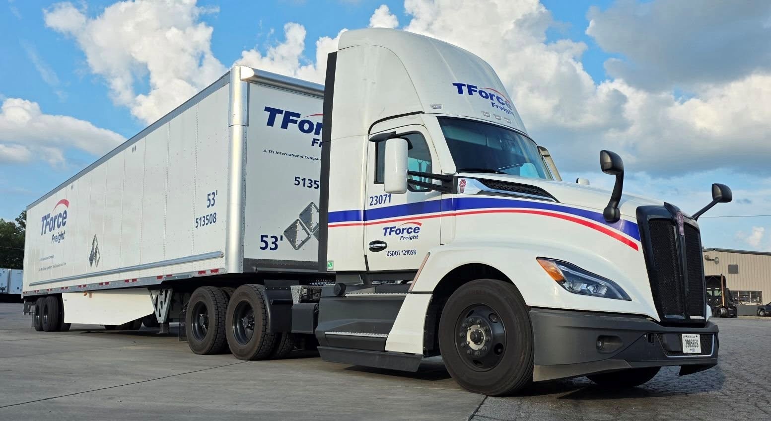 White TForce Freight tractor and 53-foot trailer parked beneath a cloud-filled sky