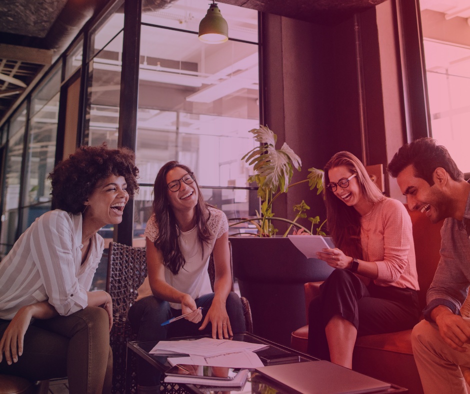 Four people gathered around a laptop in a promotional collaboration photograph used by TG Federal