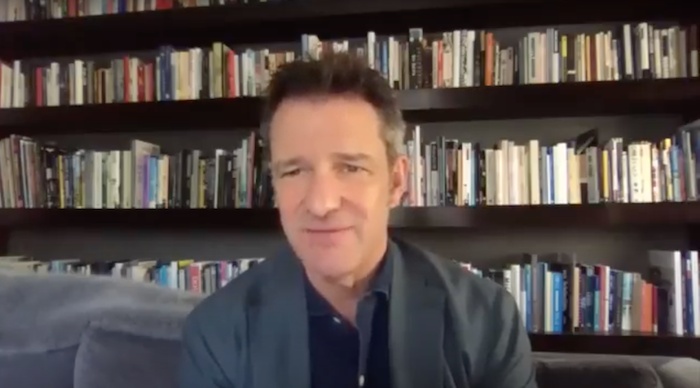 Thane Kerner speaking in a Hum introduction video, seated in front of bookshelves