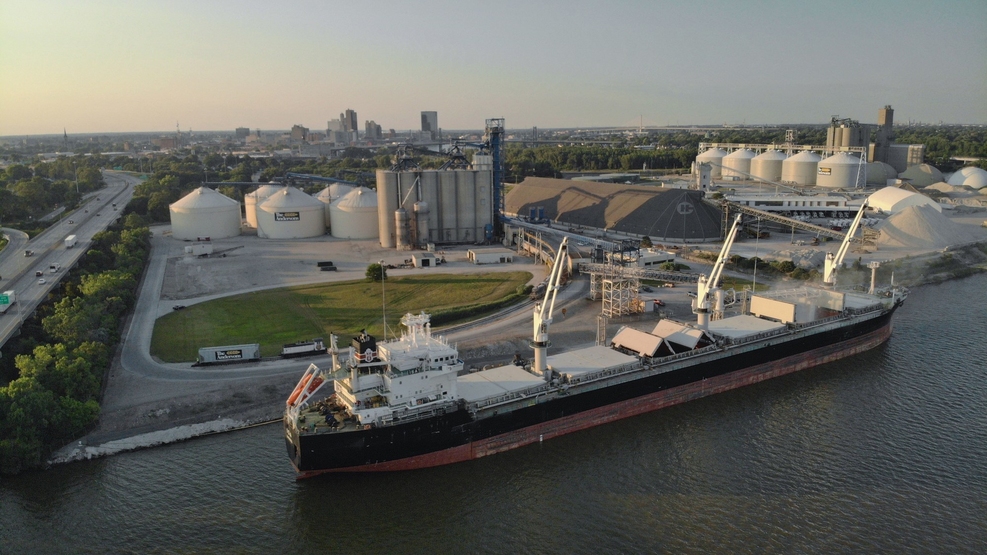 A cargo vessel alongside grain silos and loading equipment at The Andersons river facility