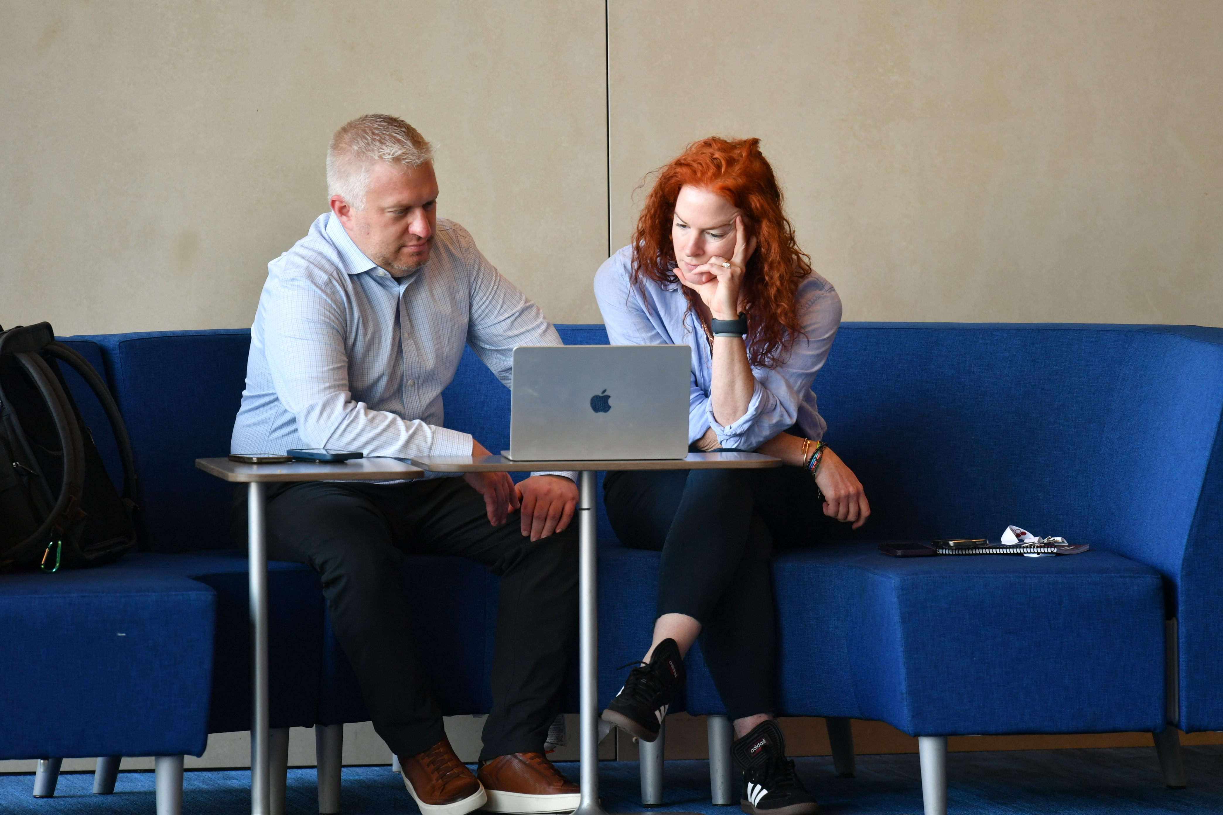 Two people concentrating on a laptop while seated on a blue sofa