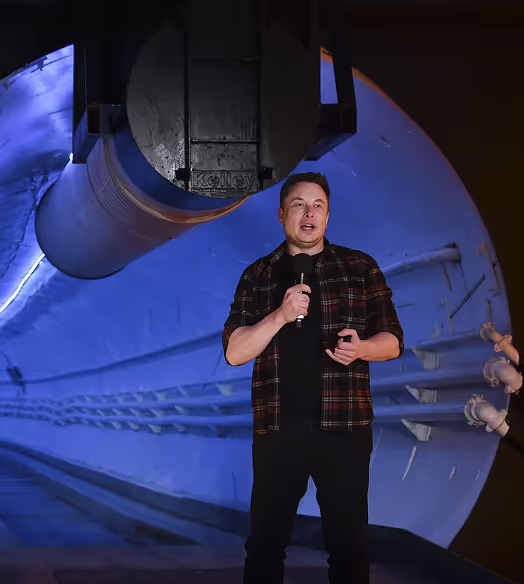 Elon Musk speaking with a microphone inside a tunnel