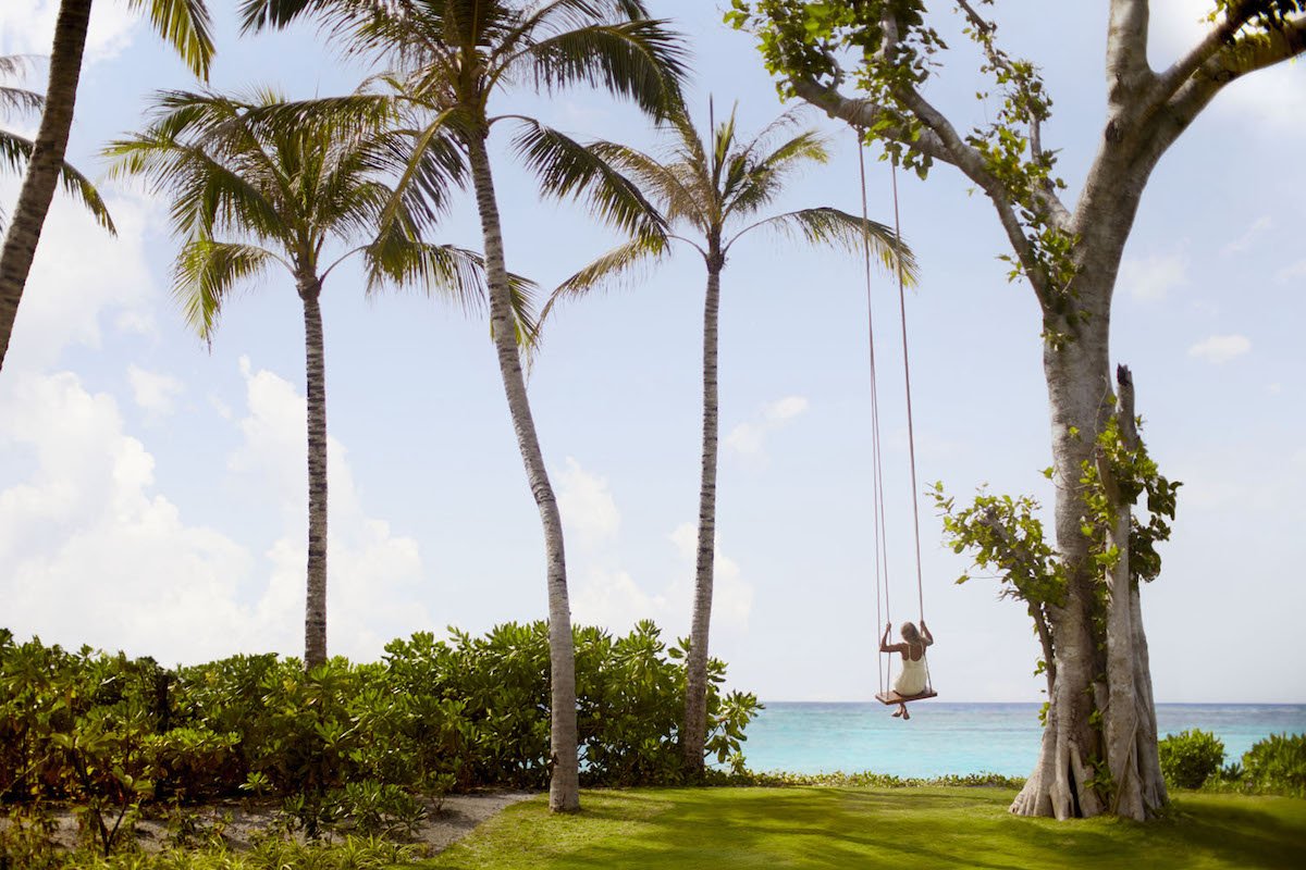 A guest on a swing beside the ocean at The Ritz-Carlton Maldives, Fari Islands