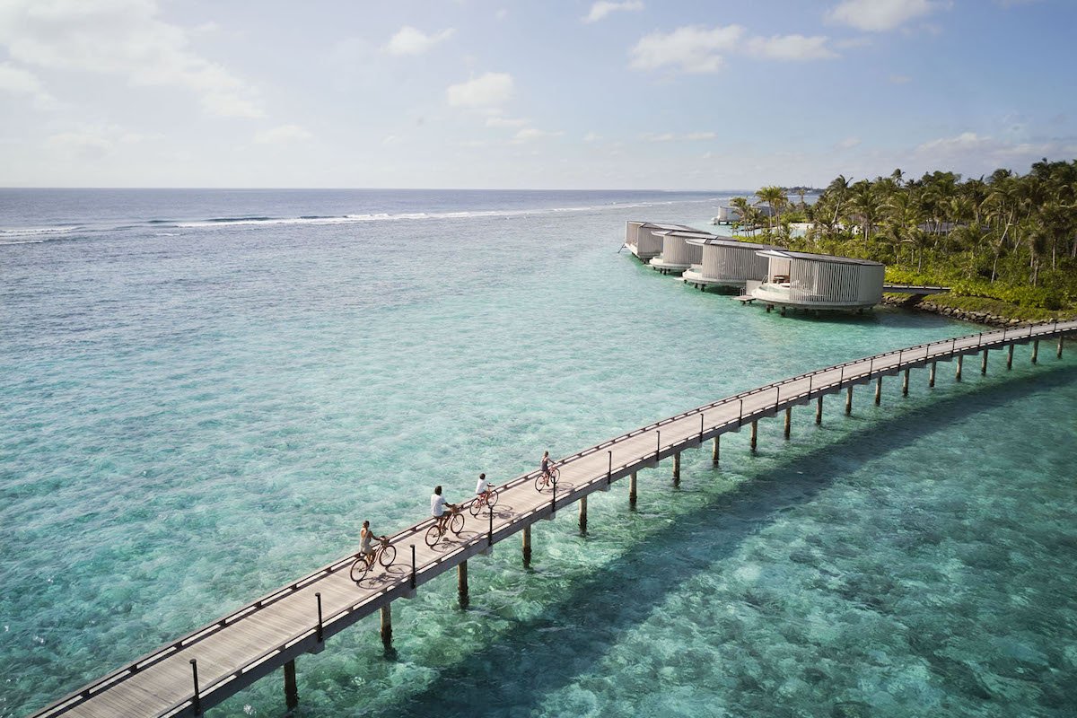 Guests cycling above turquoise water at The Ritz-Carlton Maldives, Fari Islands