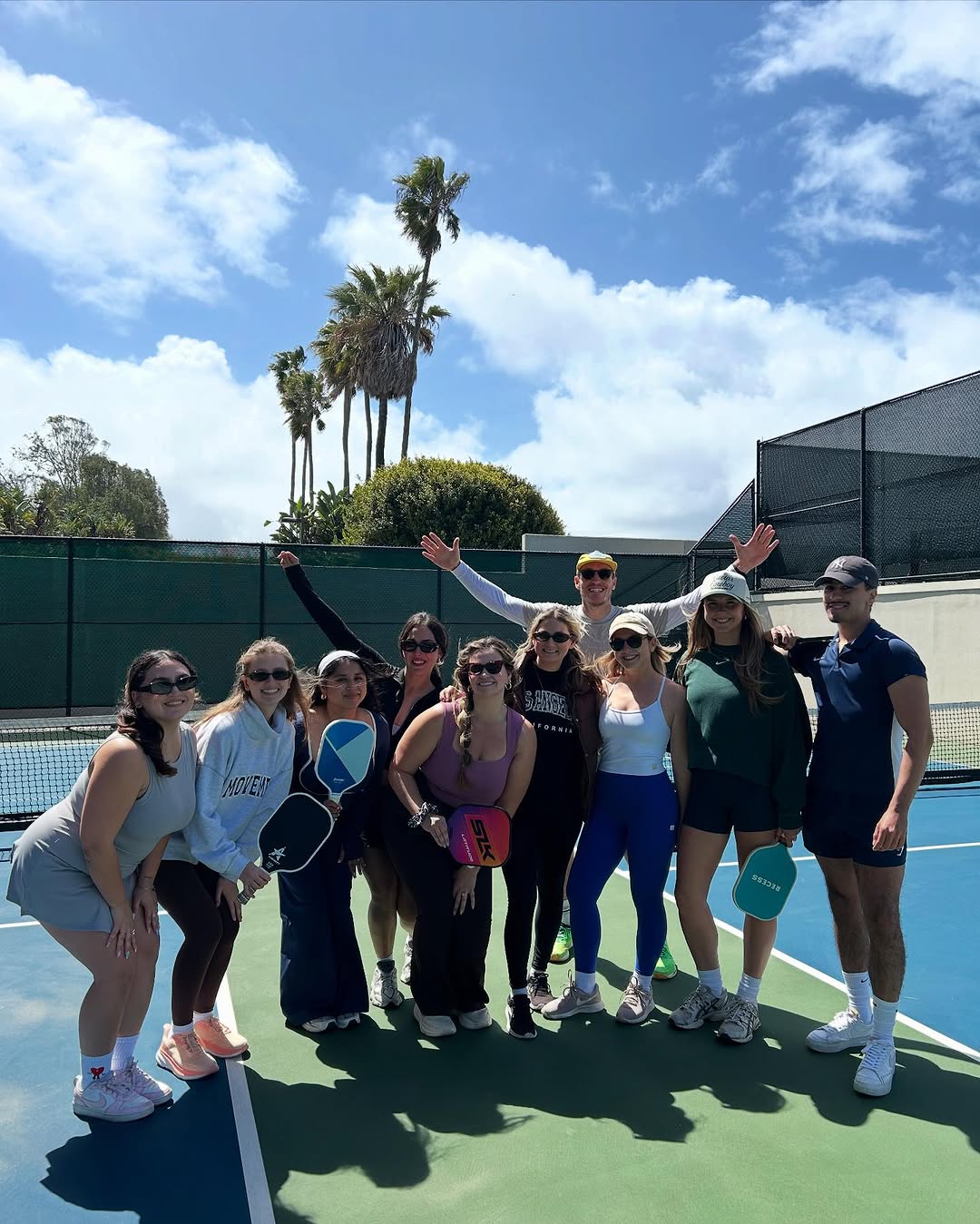 Group pictured on a sunny pickleball court in the photographs accompanying Susan Rapaglia’s interview