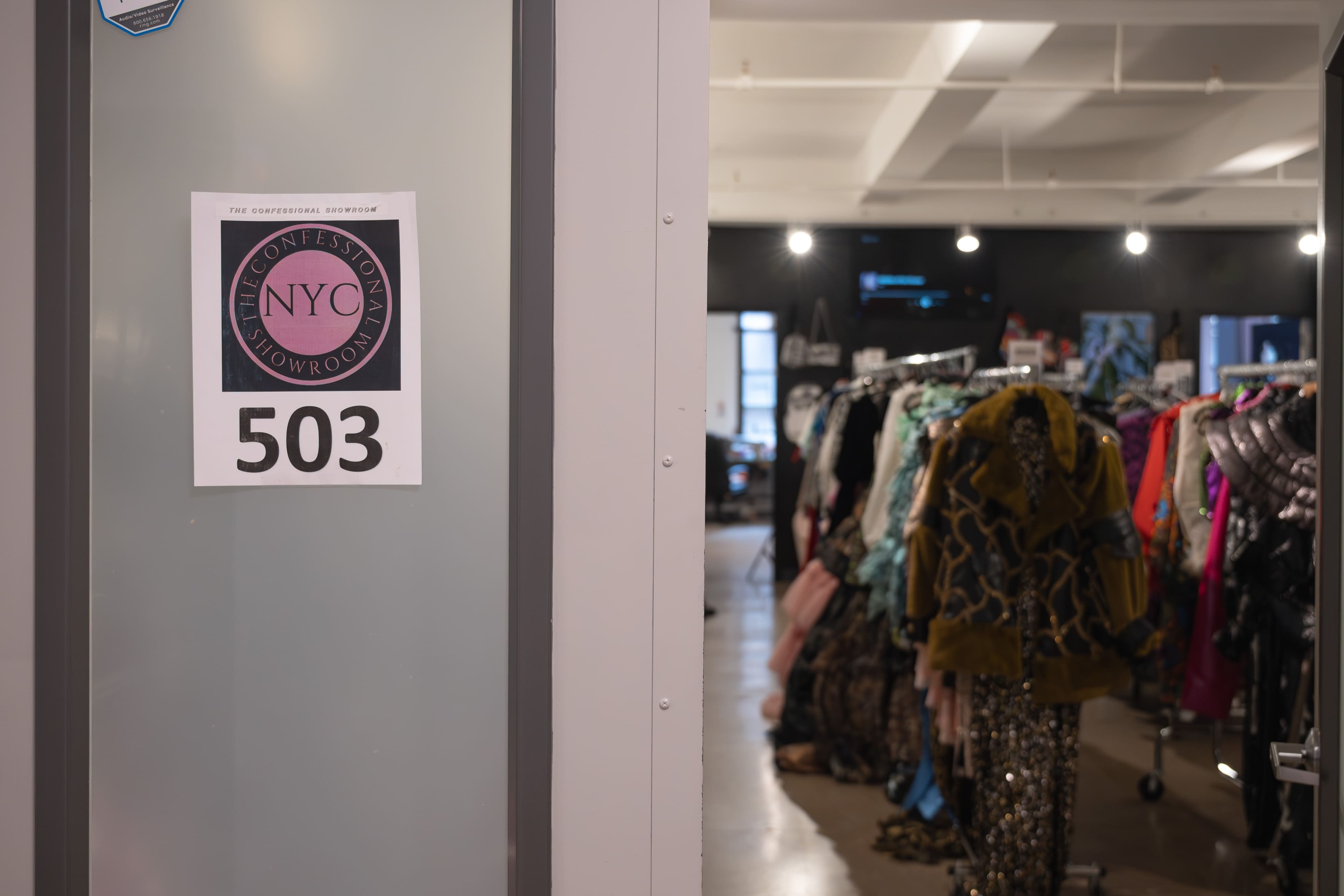 The glass entrance to The Confessional Showroom opening onto racks of designer clothing
