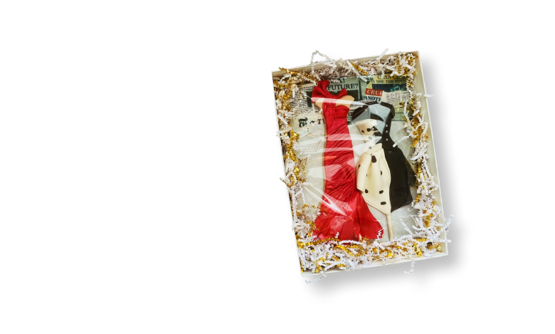 Two miniature Cruella chocolate costumes nestled in a presentation box