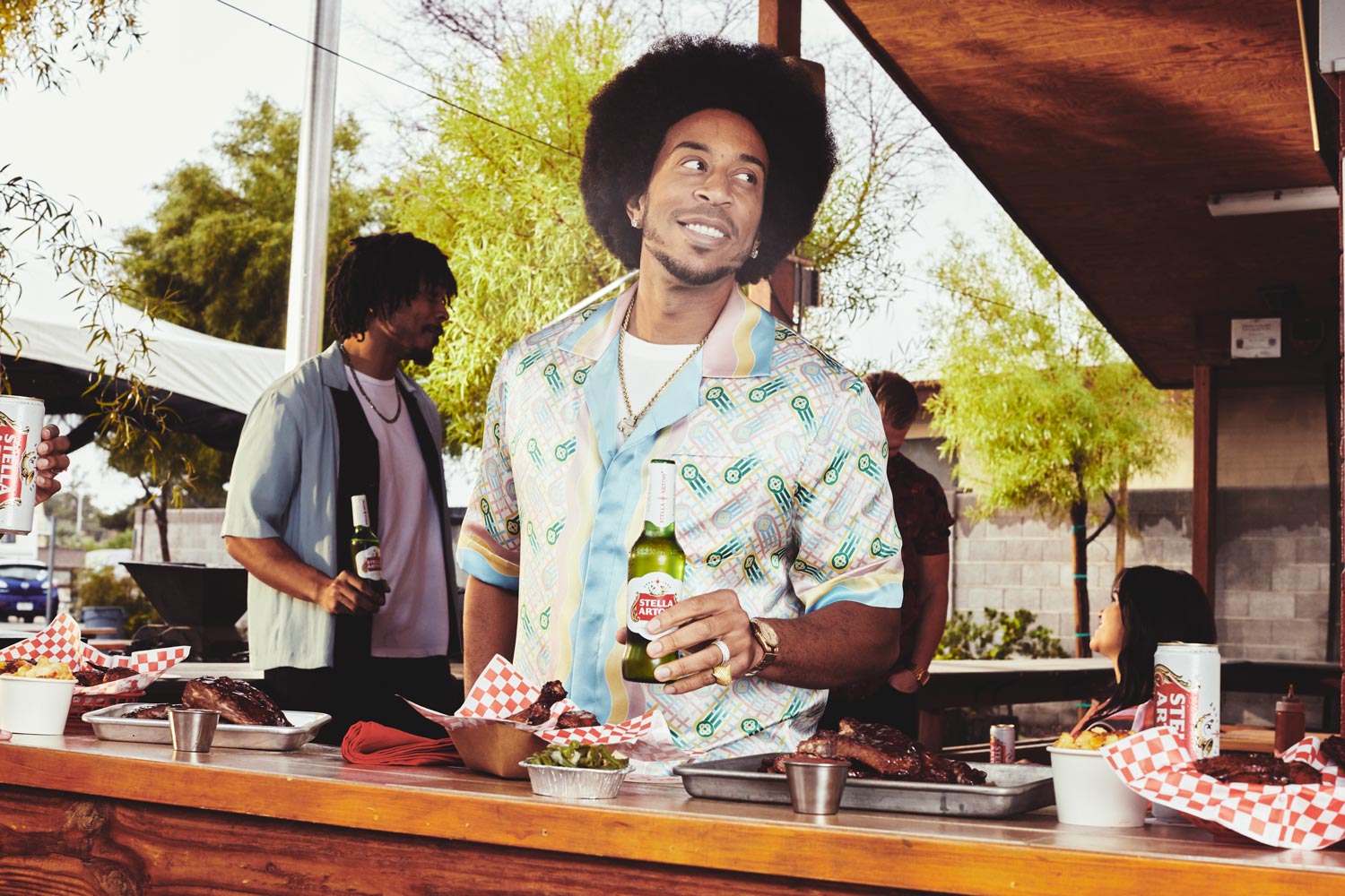 Ludacris holding a Stella Artois bottle at a barbecue restaurant during a campaign shoot