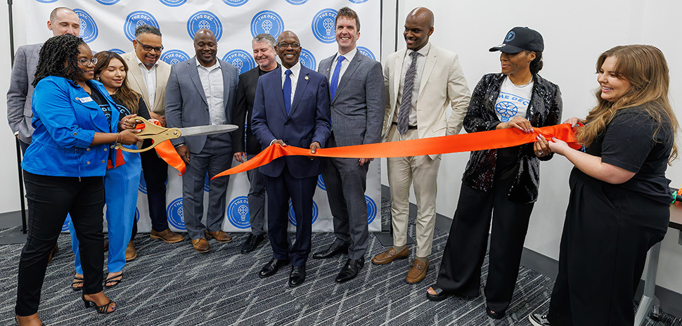 Community members and DEC leaders cut an orange ribbon at the expanded RedBird center