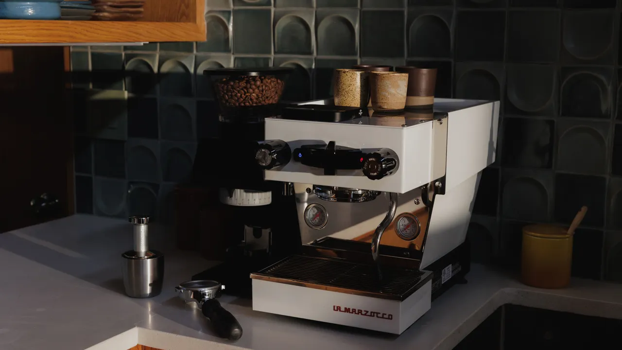 A white La Marzocco espresso machine in a teal kitchen, featured with the coffee episode