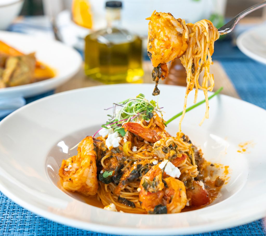 Fork lifting seafood pasta from a white restaurant bowl