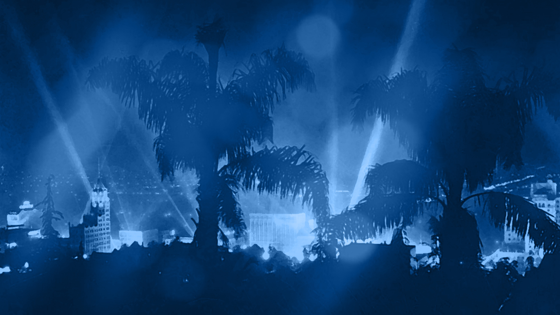 A blue-toned festival night scene with palm trees and sweeping lights