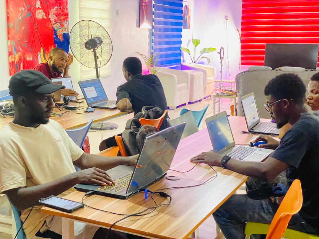 People working on laptops around shared tables in The Growth Hub’s colorful Akure office