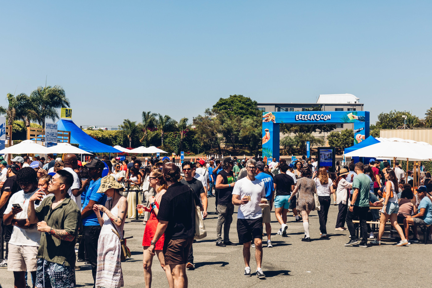 Visitors eating and walking among restaurant stands at EEEEEATSCON in Los Angeles