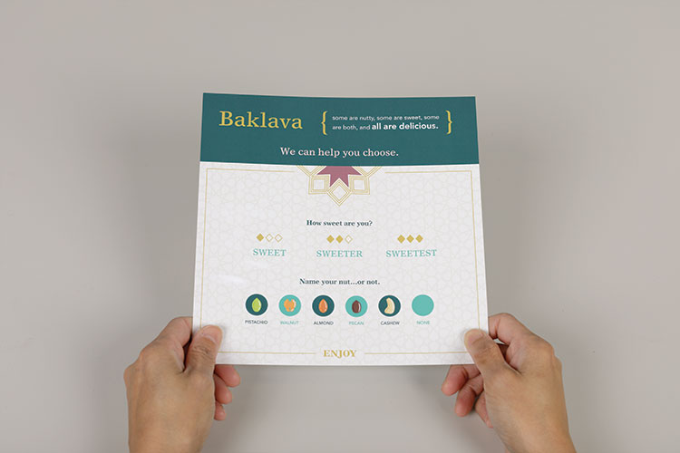 Hands holding the Loft’s Sedara baklava guide, showing sweetness levels and nut varieties