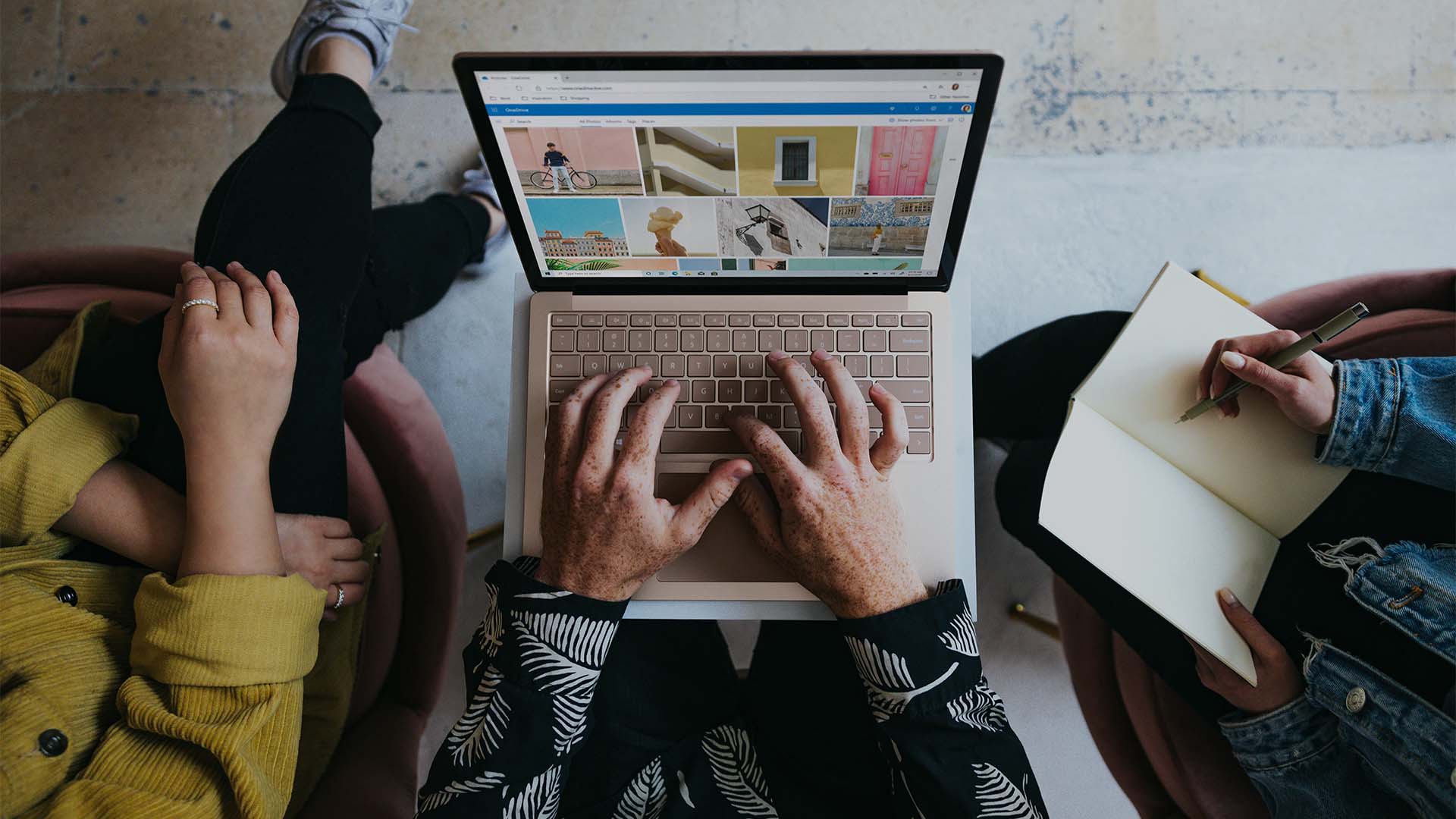 Three collaborators work around a laptop and notebook