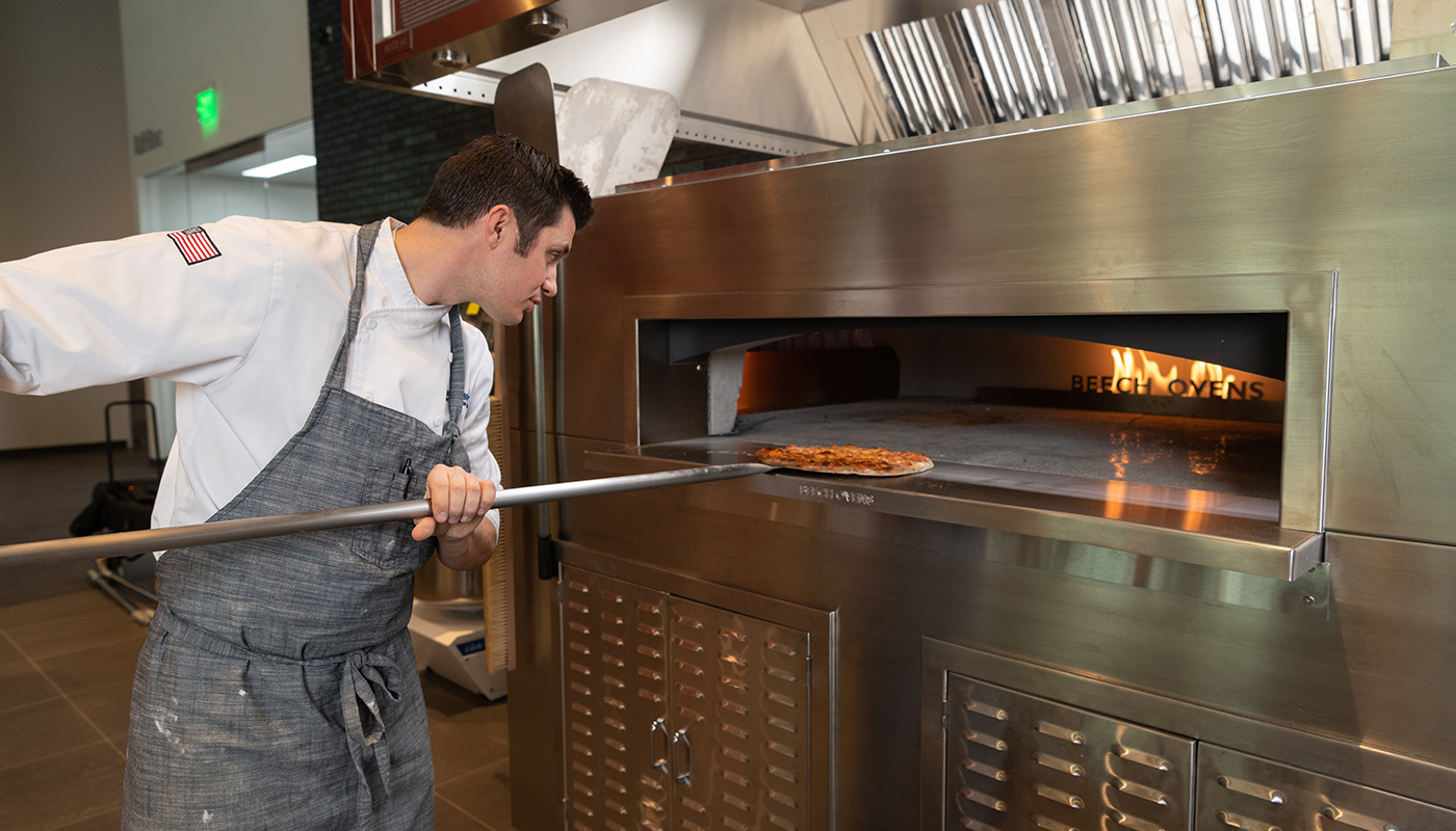Chef Kyle Wilson tending a pizza in a Beech oven at Middleby Innovation Kitchens