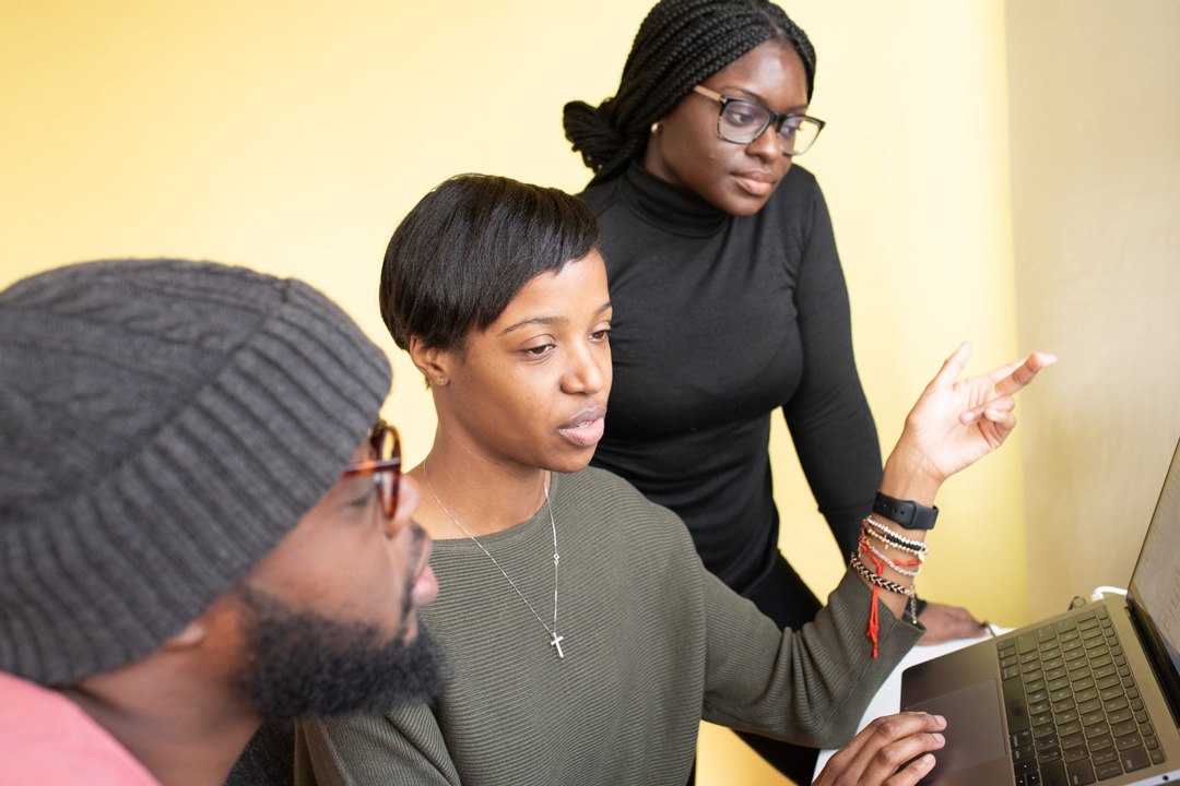 Members of The Mosaic Group team collaborating around a laptop