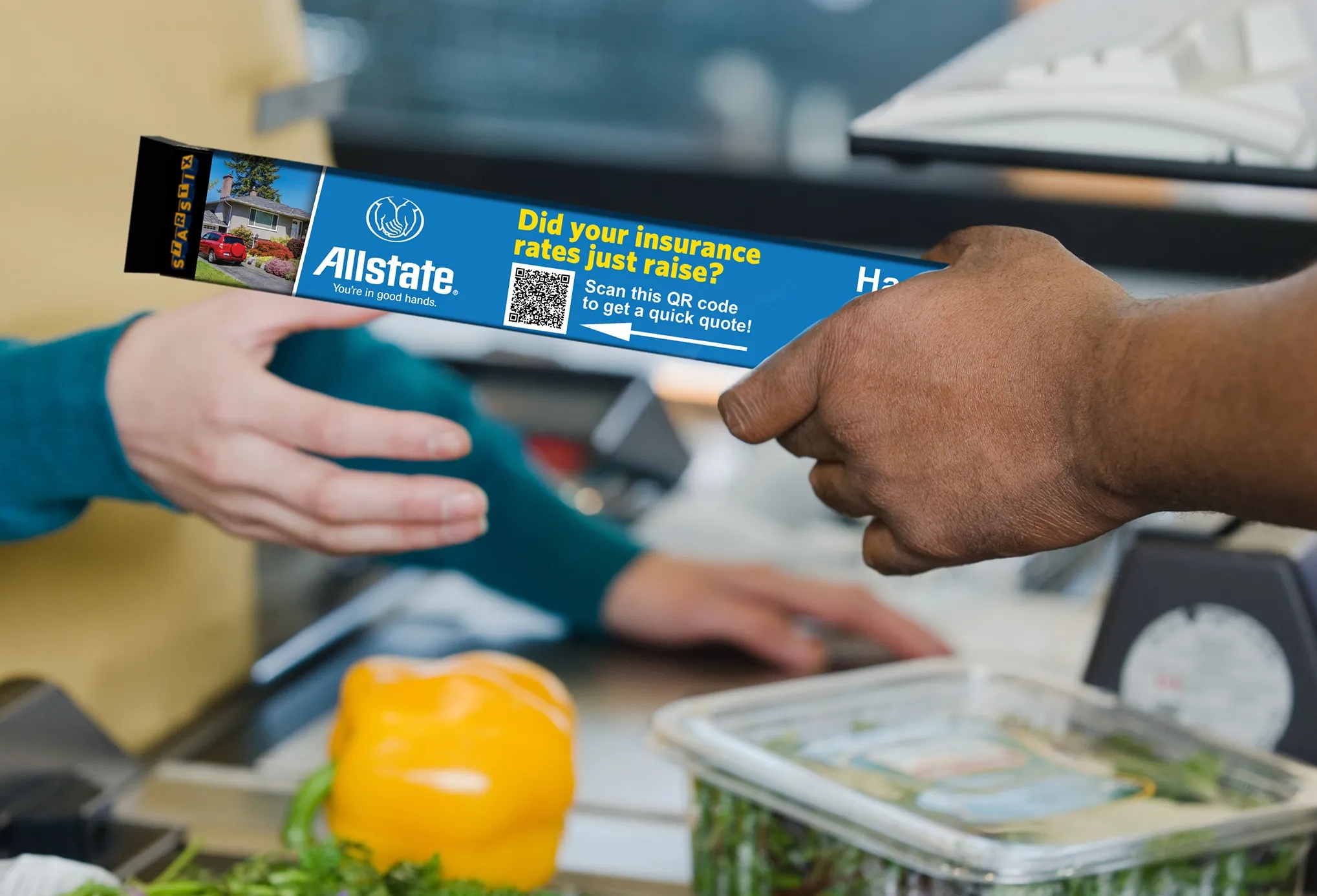 A STARSTIX checkout divider displaying an Allstate insurance advertisement and QR code, held above groceries.