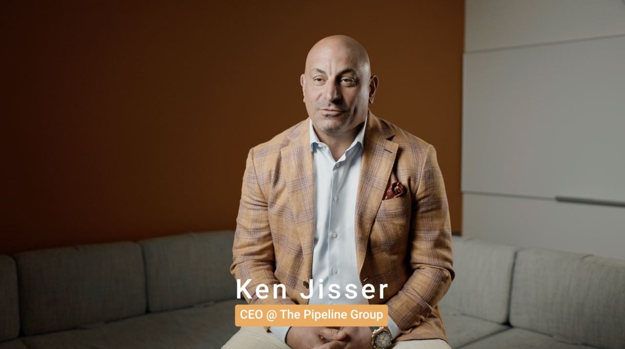 Ken Jisser seated for a company interview in a tan checked jacket