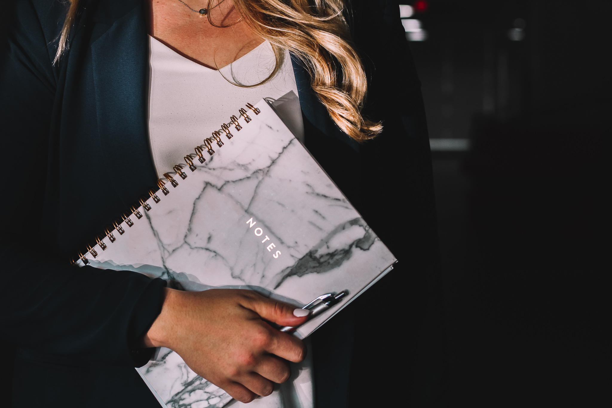 A communications professional holding a marble-patterned notebook and pen
