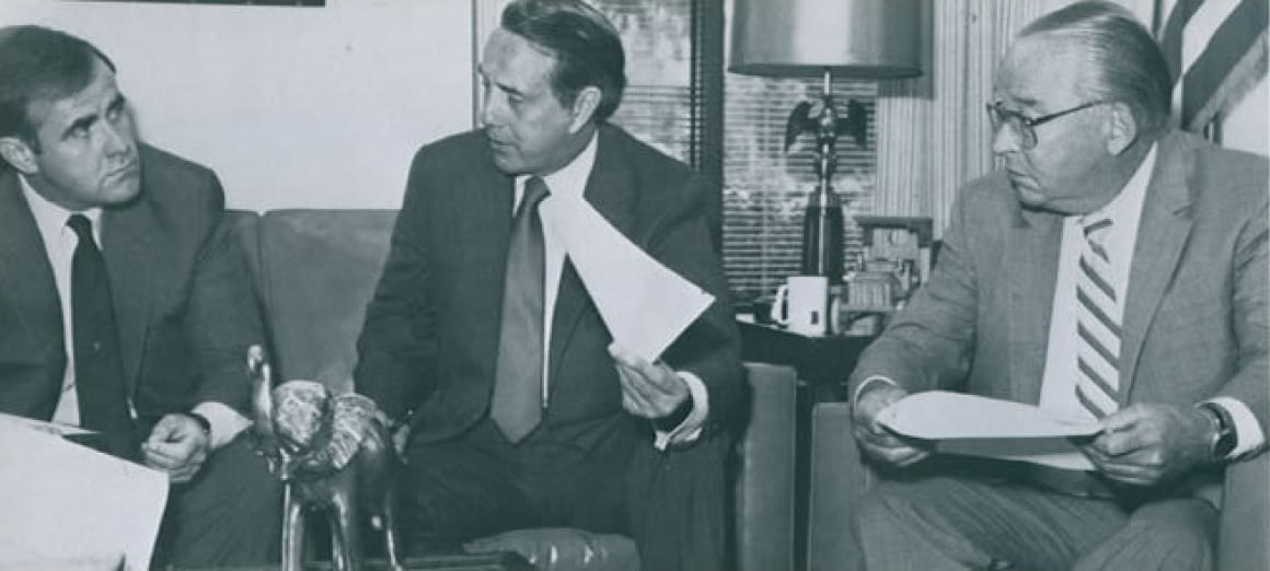 Three early leaders of The Russell Group's predecessor firm discussing papers in an office
