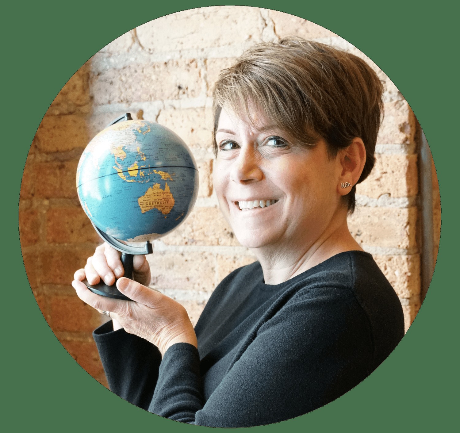 Beth Silverman holding a small globe in front of a brick wall