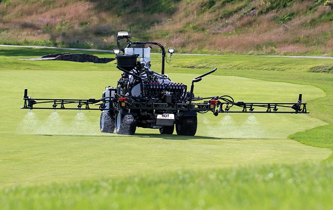 Rear view of a Toro Multi Pro turf sprayer applying material across a golf green