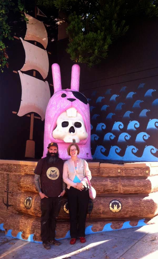 Artist Jeremy Fish and Thea Selby standing beneath Fish’s pink pirate bunny sculpture in the Lower Haight