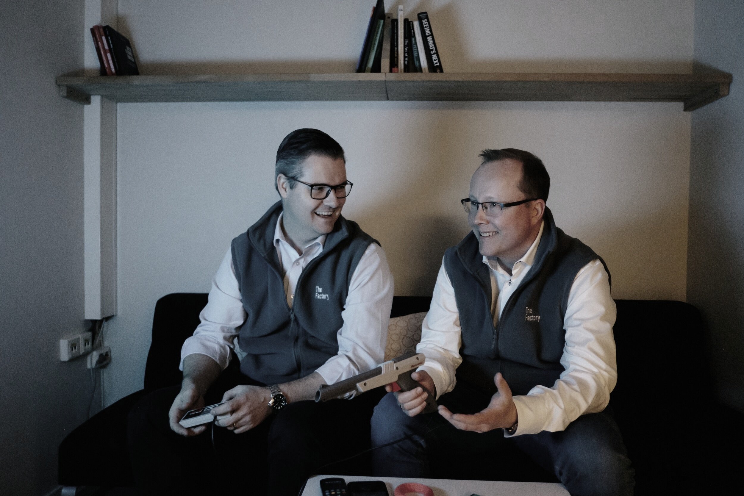 TheFactory founders seated together holding retro game controllers