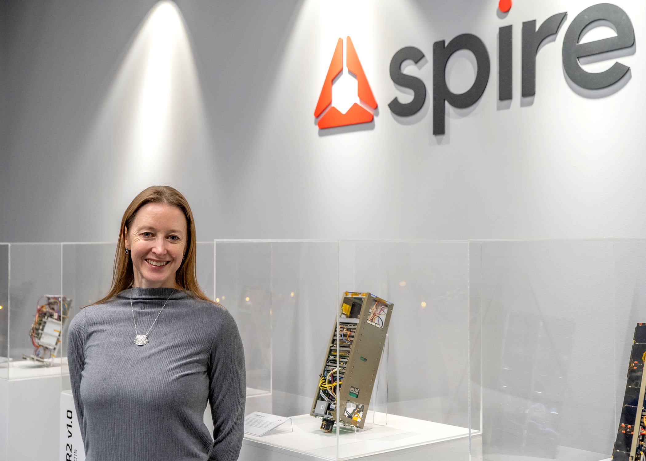 Theresa Condor standing beside satellite displays at Spire’s Glasgow manufacturing center