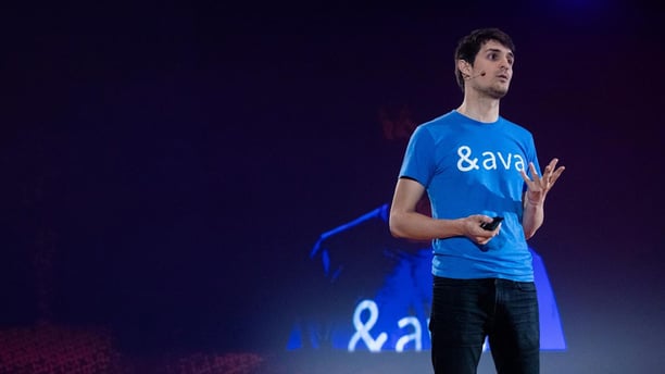 Thibault Duchemin on stage, wearing a blue Ava T-shirt and gesturing as he speaks.