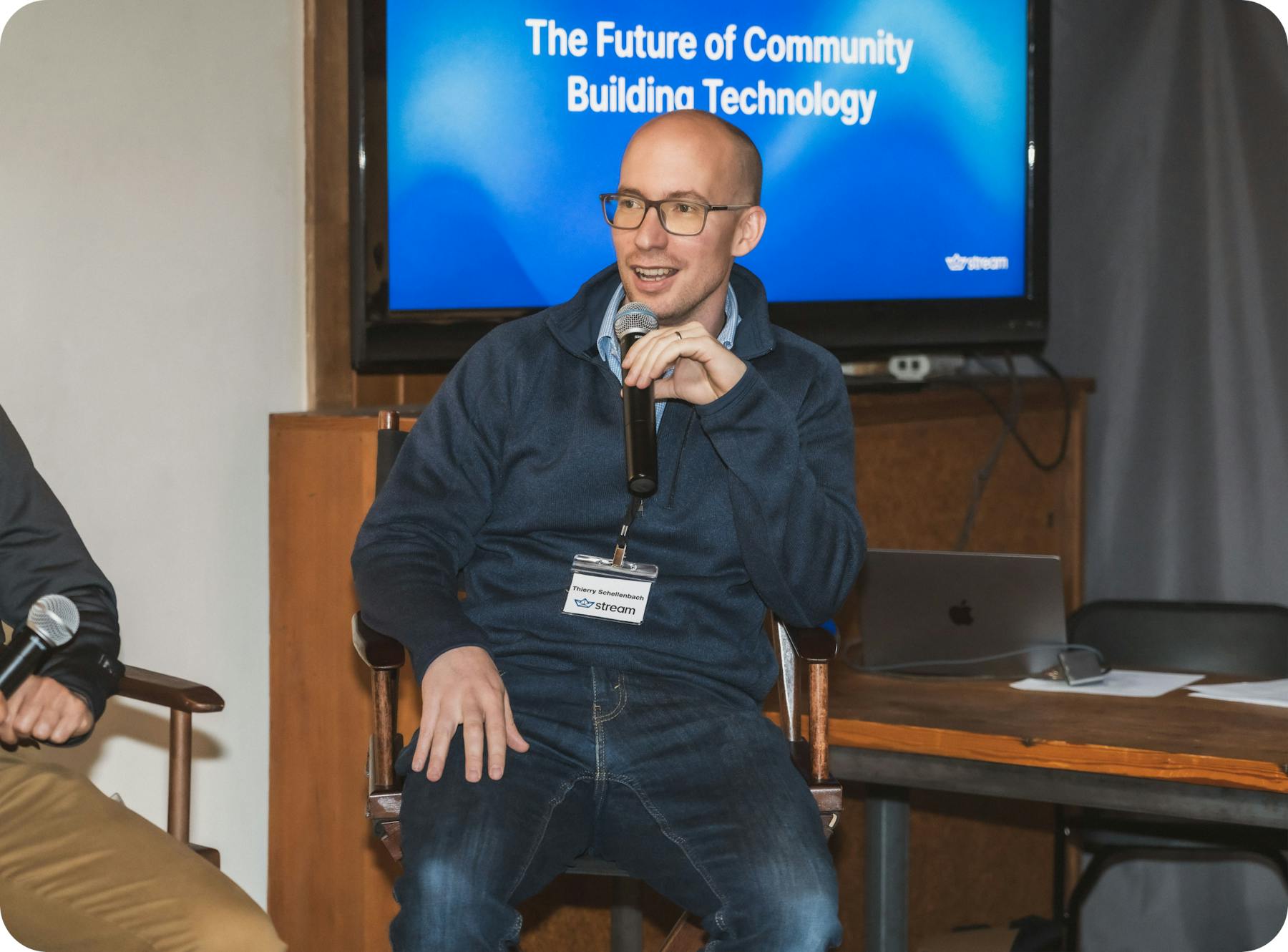 Thierry Schellenbach seated onstage with a microphone during a discussion about community-building technology
