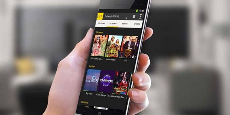 A hand holds a smartphone displaying Peel’s visual television discovery interface