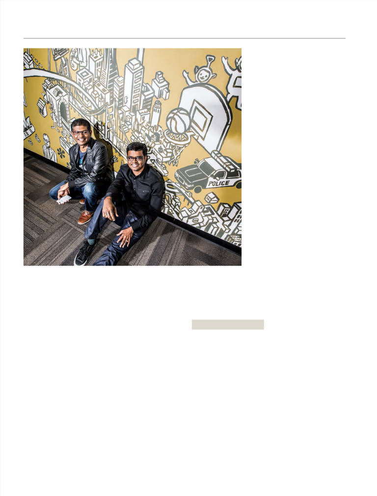 Peel co-founders Bala Krishnan, left, and Thiru Arunachalam, right, seated beside a yellow illustrated wall