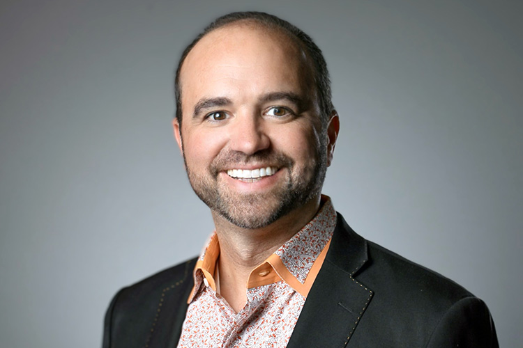 Joe Pulizzi smiling in a jacket and orange shirt
