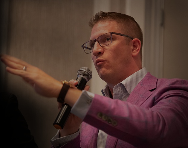 Thomas Donohoe speaking into a handheld microphone at an event