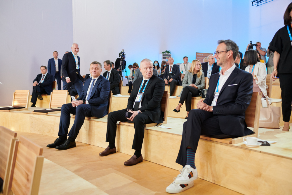 Thomas Eymond-Laritaz, seated at right in a navy suit and white trainers, with Sergiy Lovochkin and Grygorii Surkis at YES Brainstorming in 2021