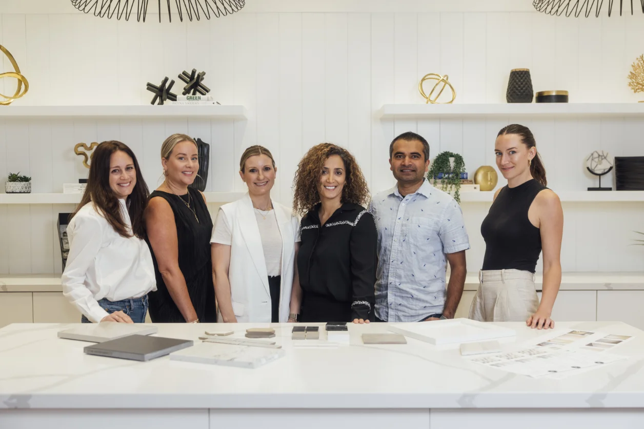 Six members of the TJH design studio team behind a counter of material samples
