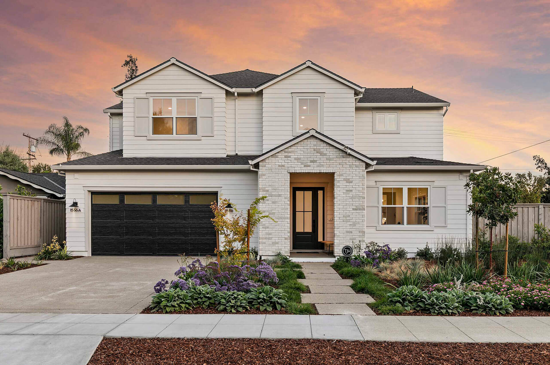 Two-story TJH Verbena home with white siding, a dark garage and landscaped front garden