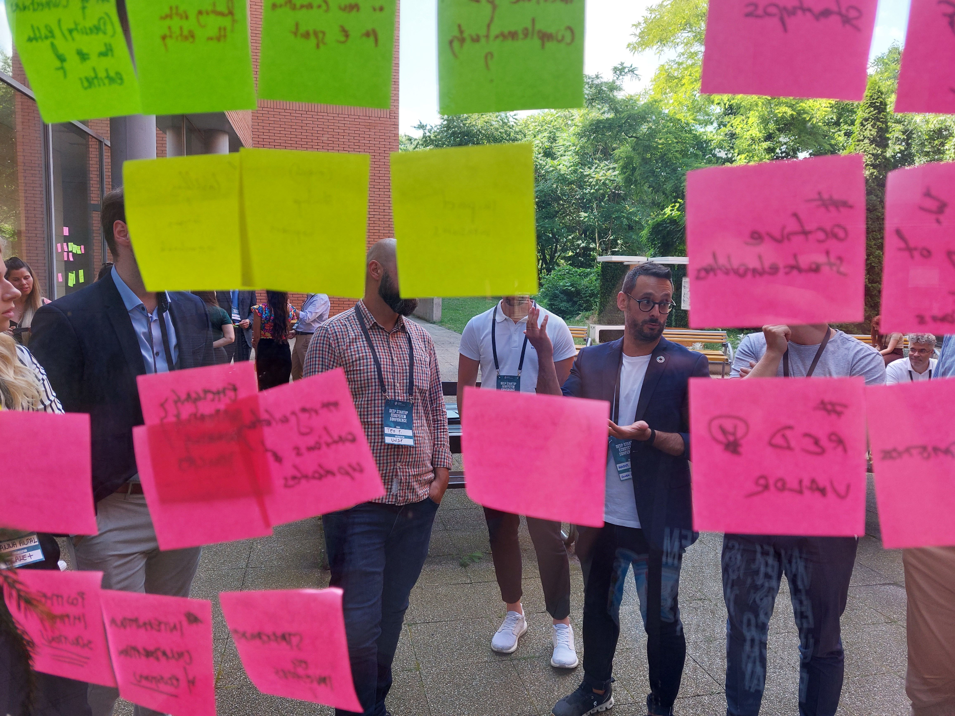 DEEP Ecosystems workshop participants discussing ideas behind a window covered in colourful sticky notes