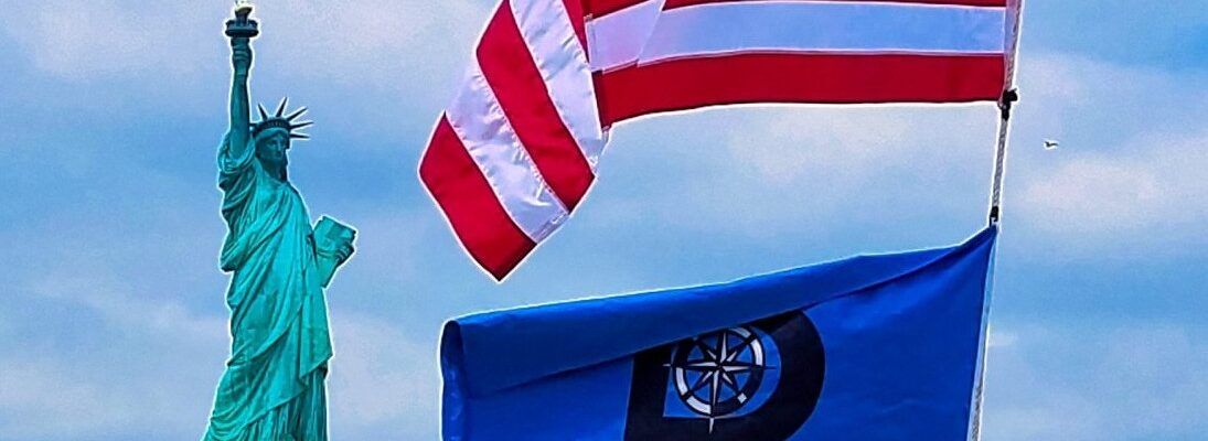 American and maritime flags with the Statue of Liberty in the background