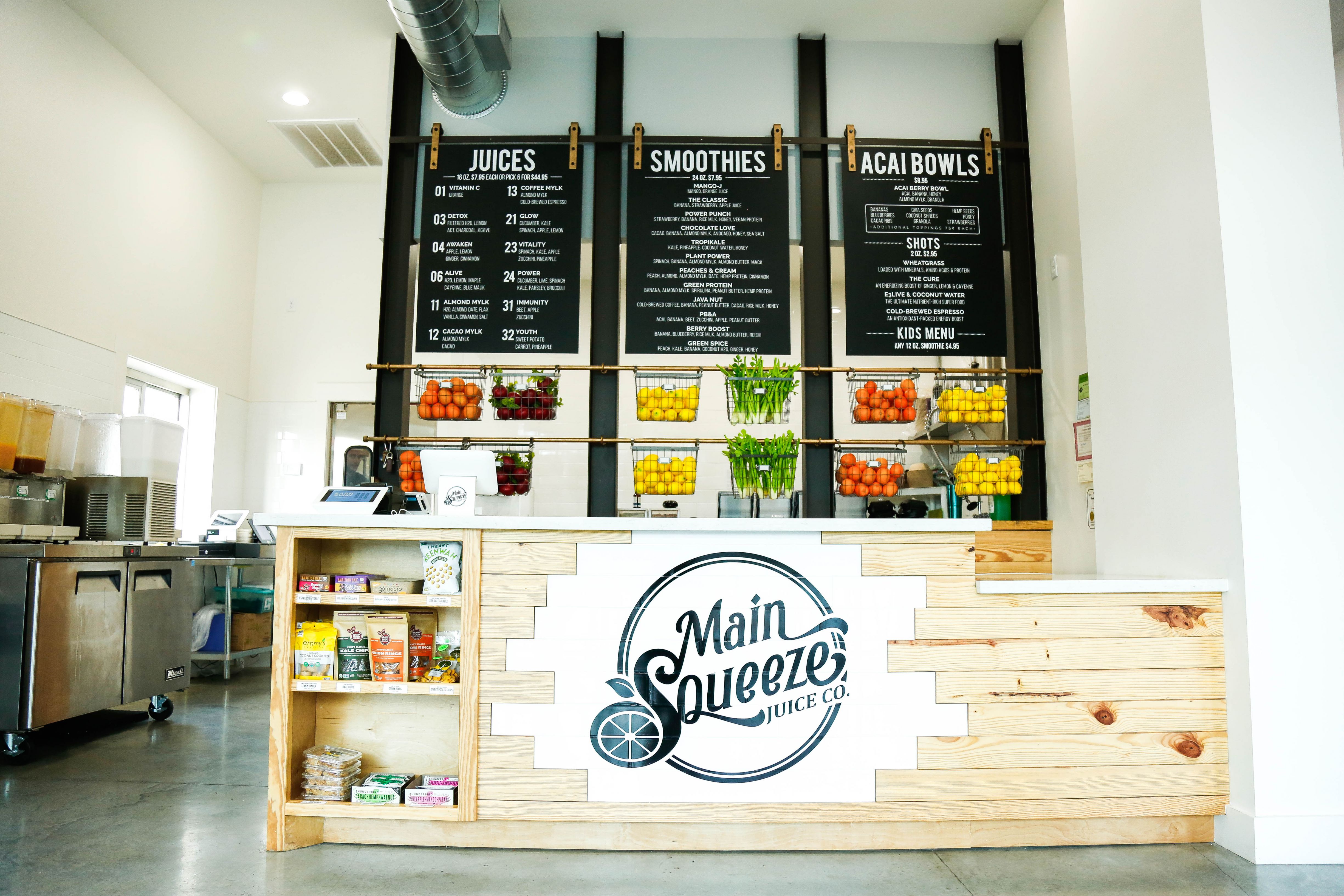 A Main Squeeze store counter with hanging fruit baskets and menu boards