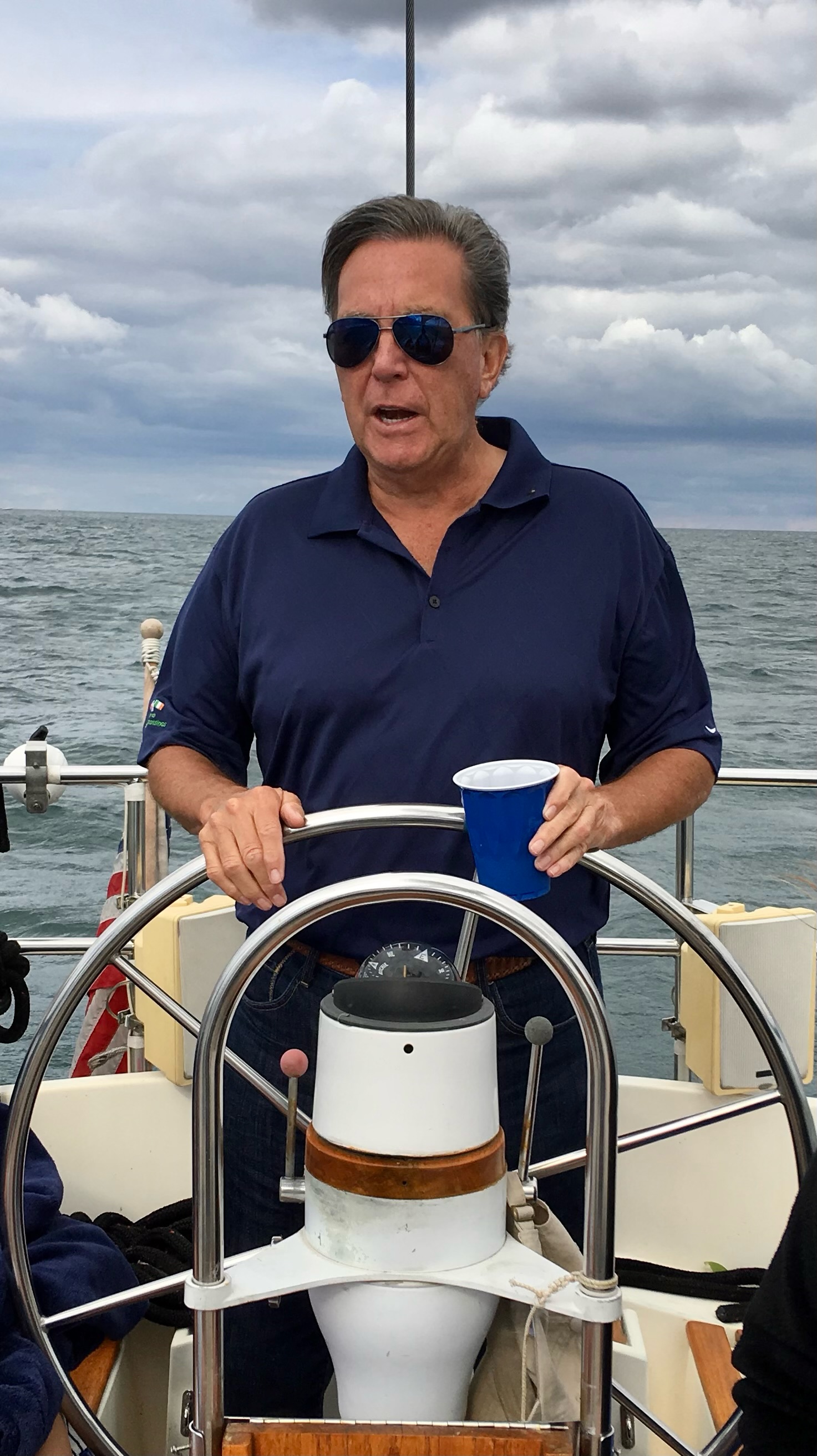 Thomas Coffey smiling at the helm of his sailboat Innisfree.