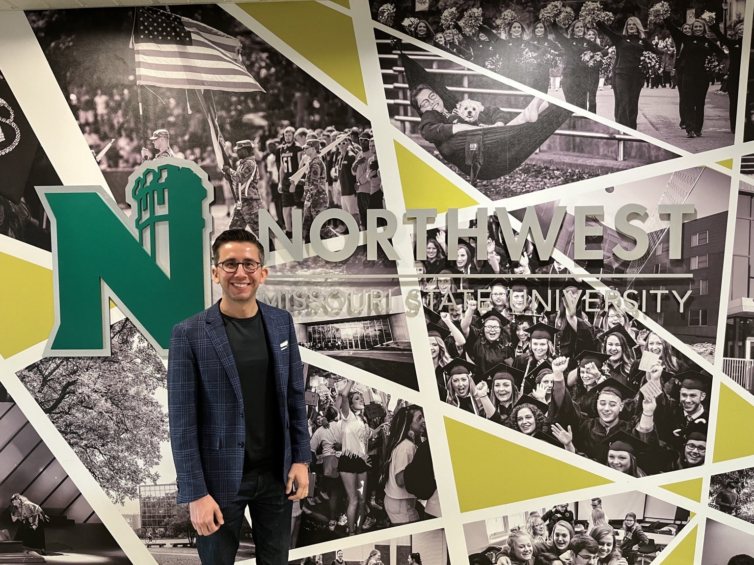 Thomas Sanchez standing beside a Northwest Missouri State University display