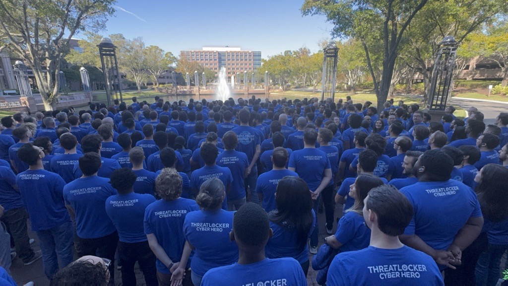 ThreatLocker Cyber Hero team members in blue shirts gathered outdoors