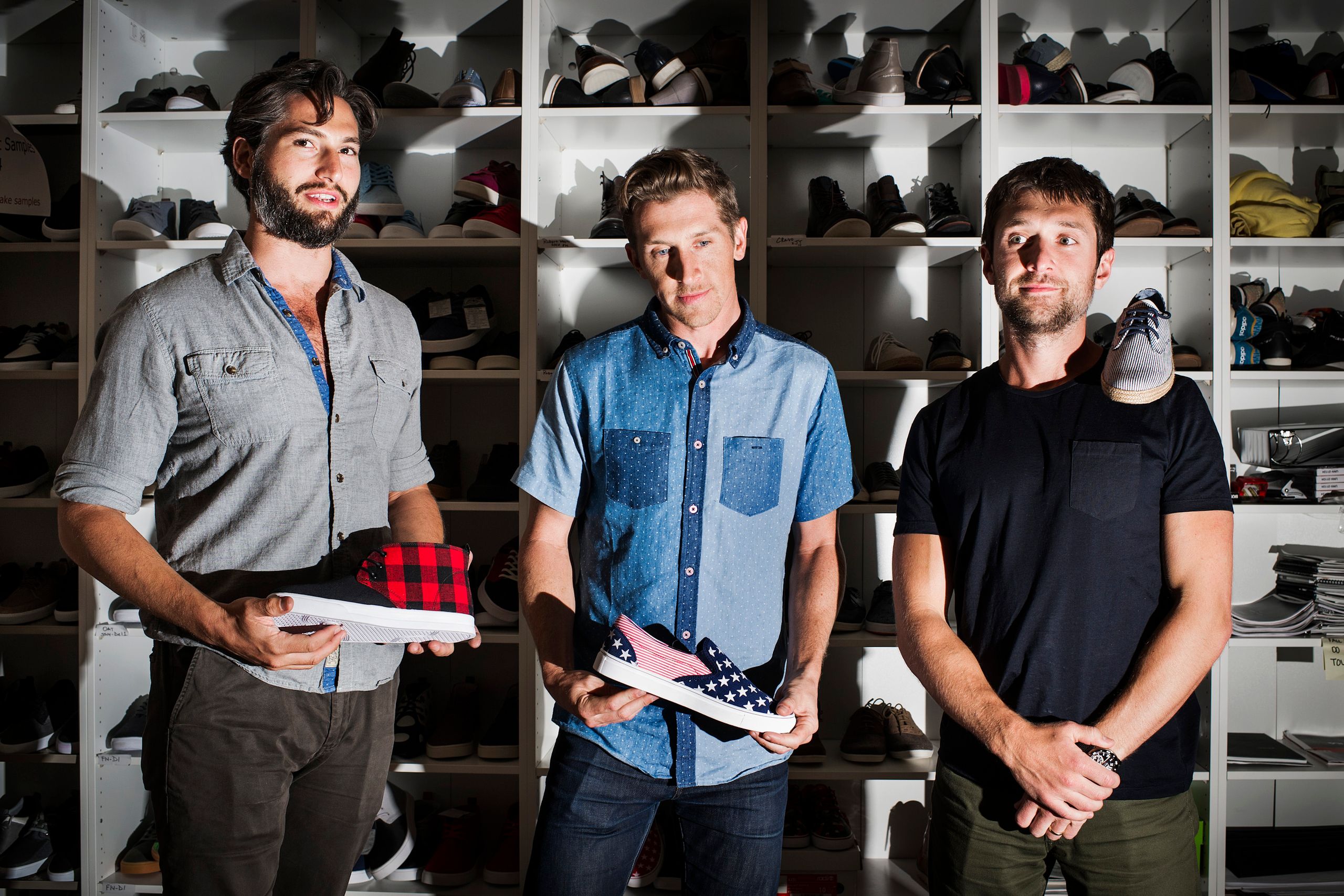Adam Rich, Jason Ross, and Ben Lerer holding shoe samples in front of shelves of footwear