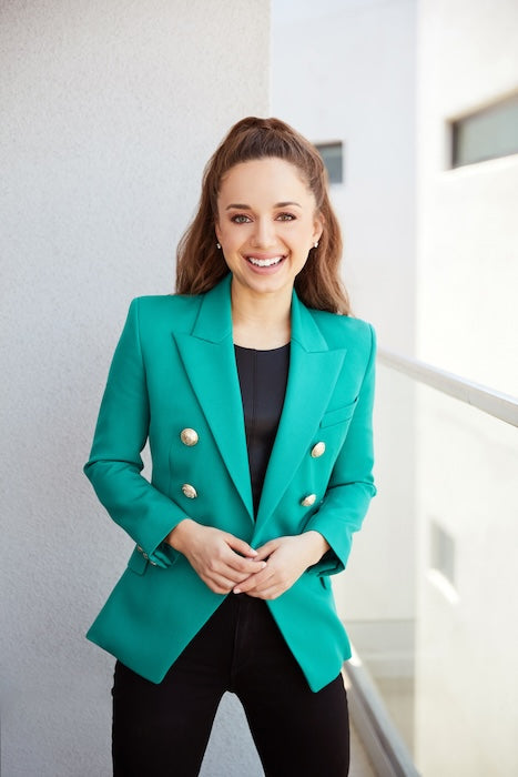 Thrive Causemetics founder Karissa Bodnar wearing a teal blazer on a balcony